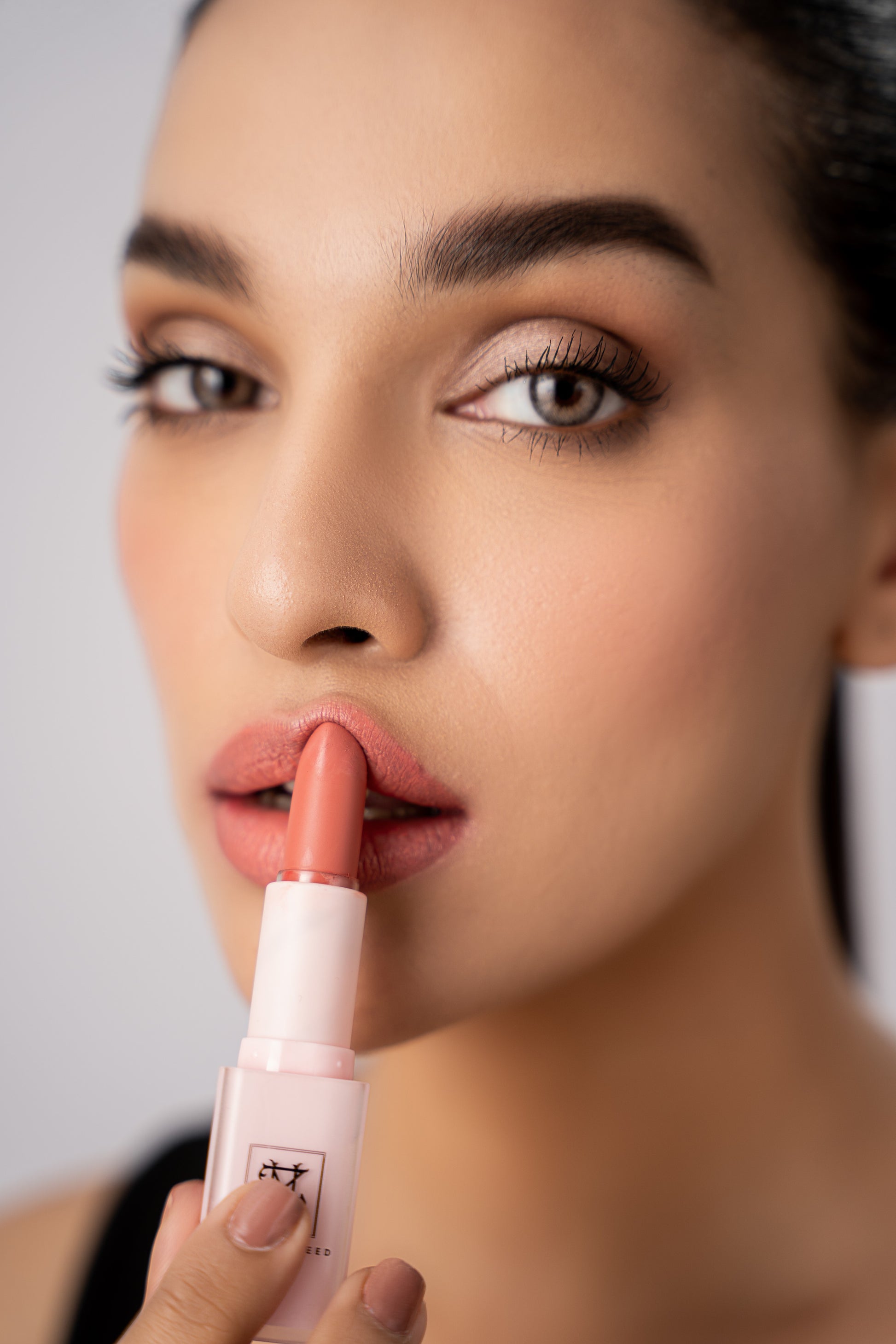 model applying nude matte lipstick by zahra naveed